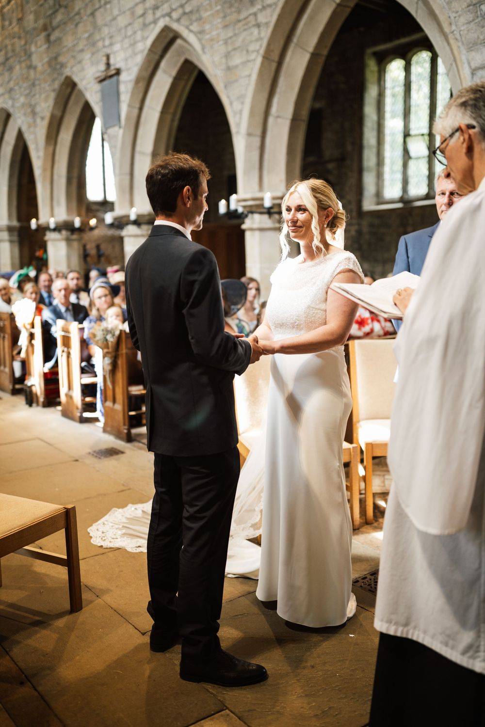 Wedding ceremony taking place in a historic stone church with gothic arches and natural lighting.