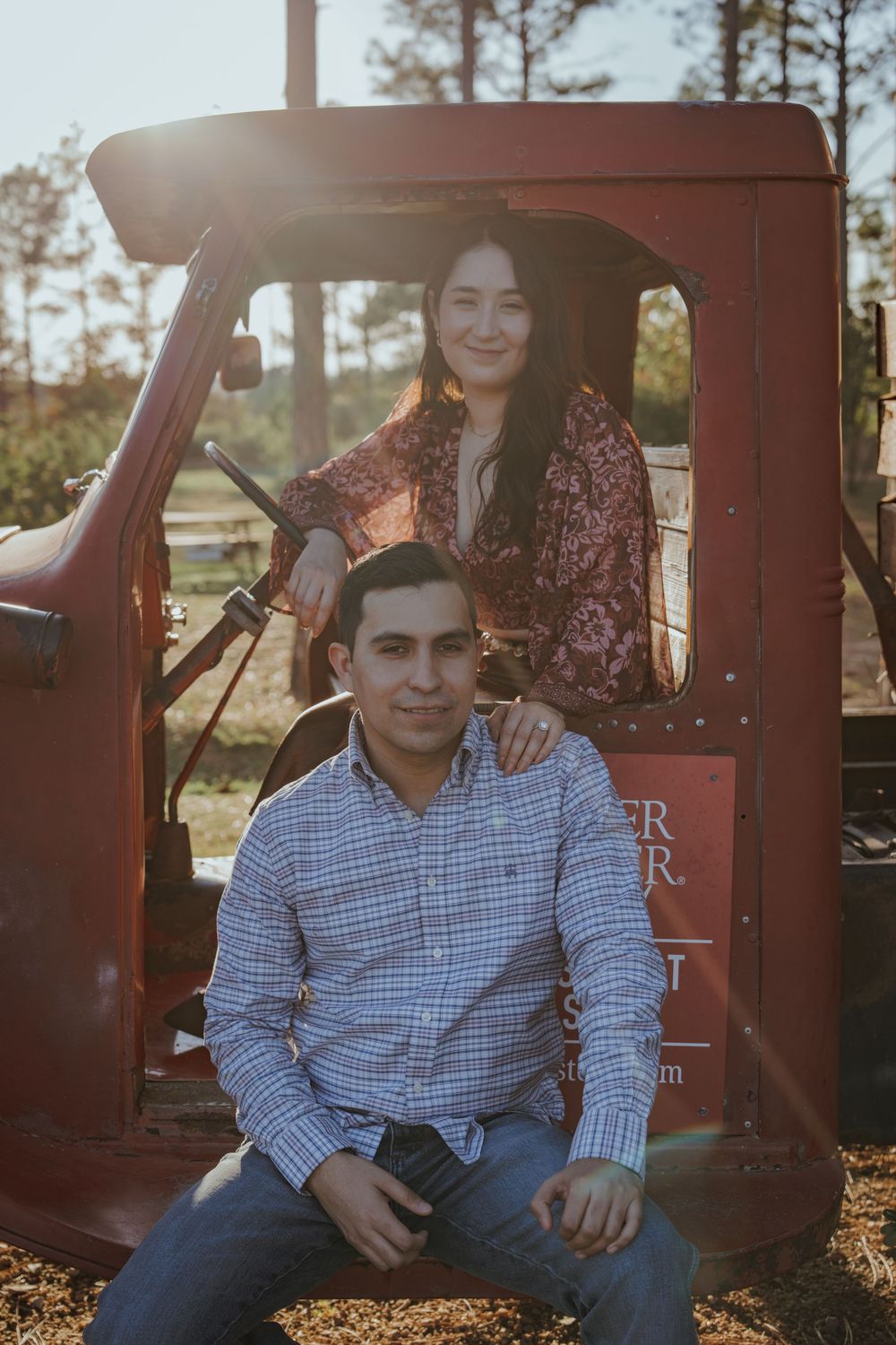 A couple shares an intimate moment while sitting in an old red truck during a sunset photoshoot.