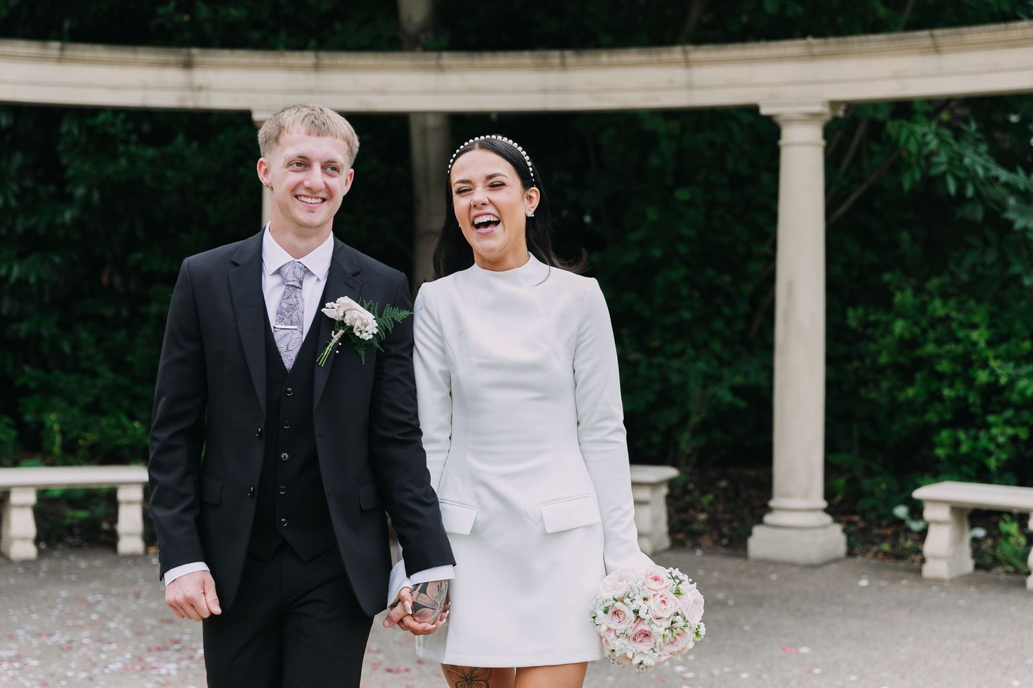 Elegant wedding couple shares a joyful moment under a white columned pergola. Photographer. Hull. East Yorkshire.
