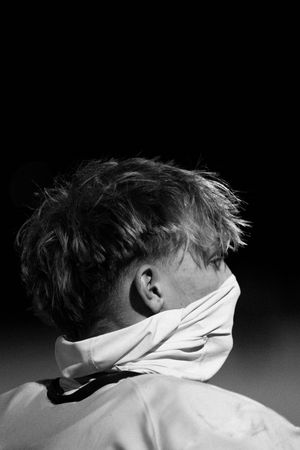 Dramatic black and white profile portrait showing hair movement against dark background.