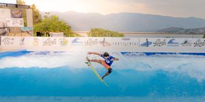 Person wakeboarding on calm water at sunset performing aerial tricks and maneuvers.