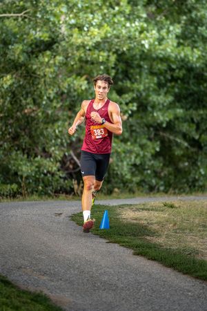 Runner in red jersey sprinting along a curved dirt path during a race.