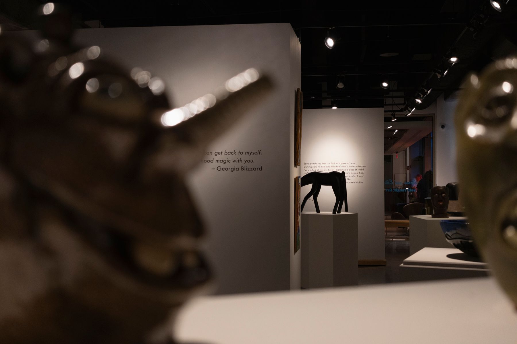 Dark gallery space with spotlights illuminating artwork displays.