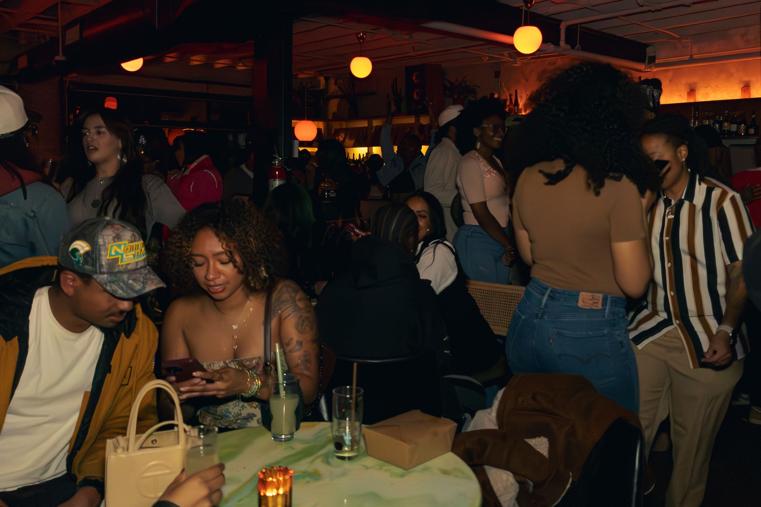 Crowded social gathering in a dimly lit venue with orange ambient lights.