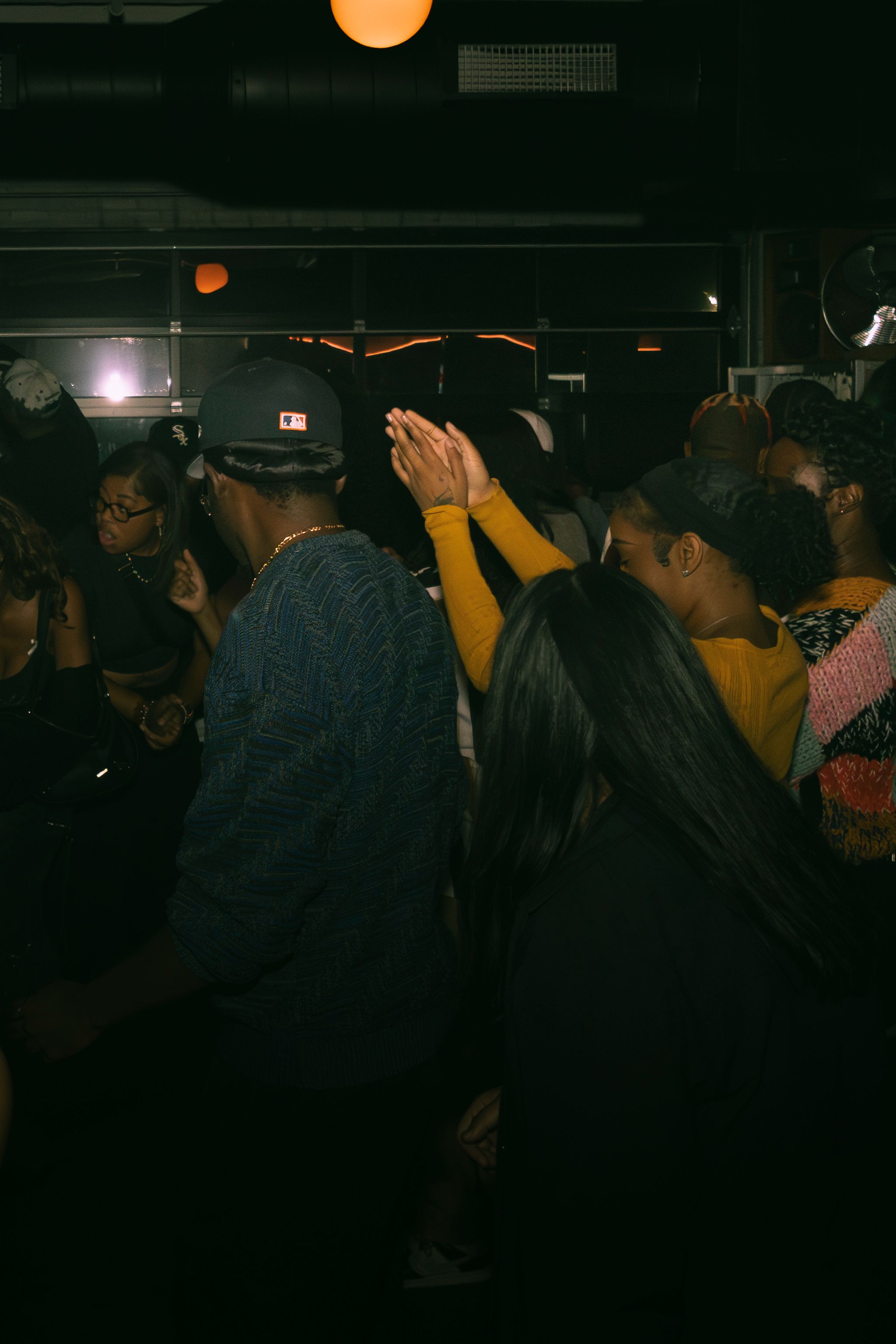 Dark venue filled with people at a social event under minimal lighting.