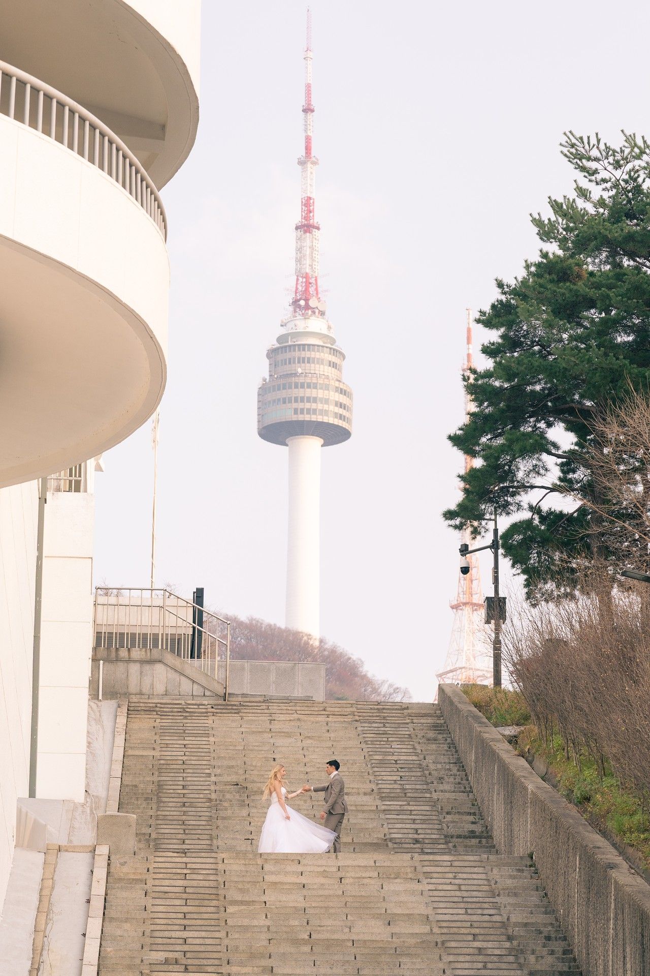 A spiral staircase leads up to N Seoul Tower in South Korea against a misty winter sky.