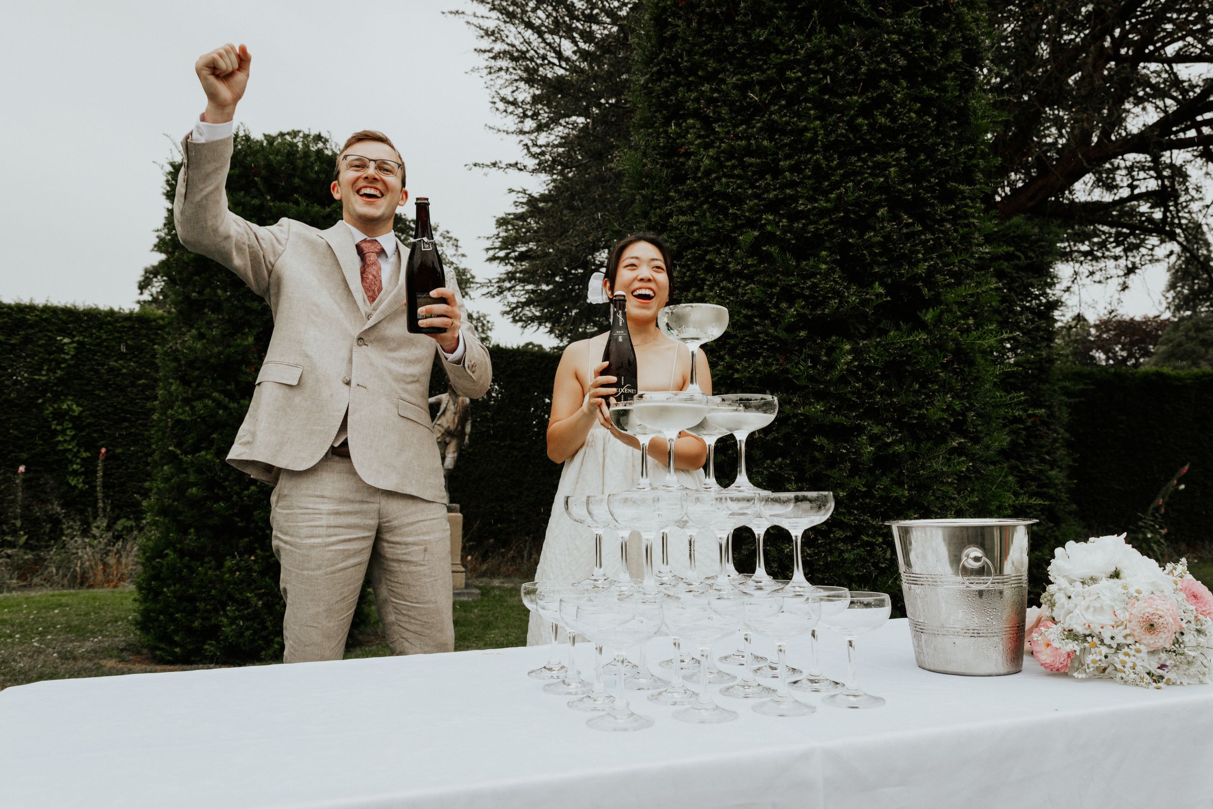 Champagne tower being poured  by Bride and Groom at Nymans Gardens wedding reception