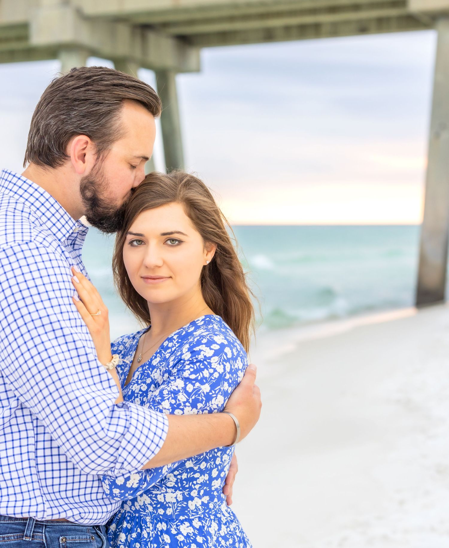 A romantic proposal scene on a white sandy beach with turquoise ocean waters in the background.