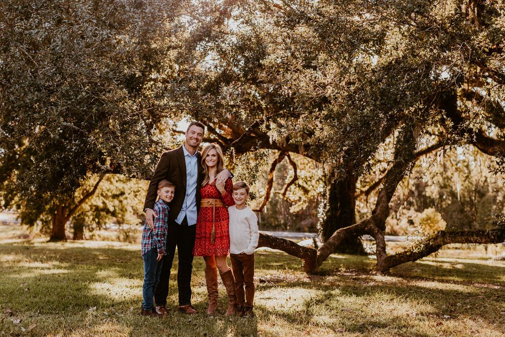 Autumn family photoshoot under golden trees in natural outdoor setting.