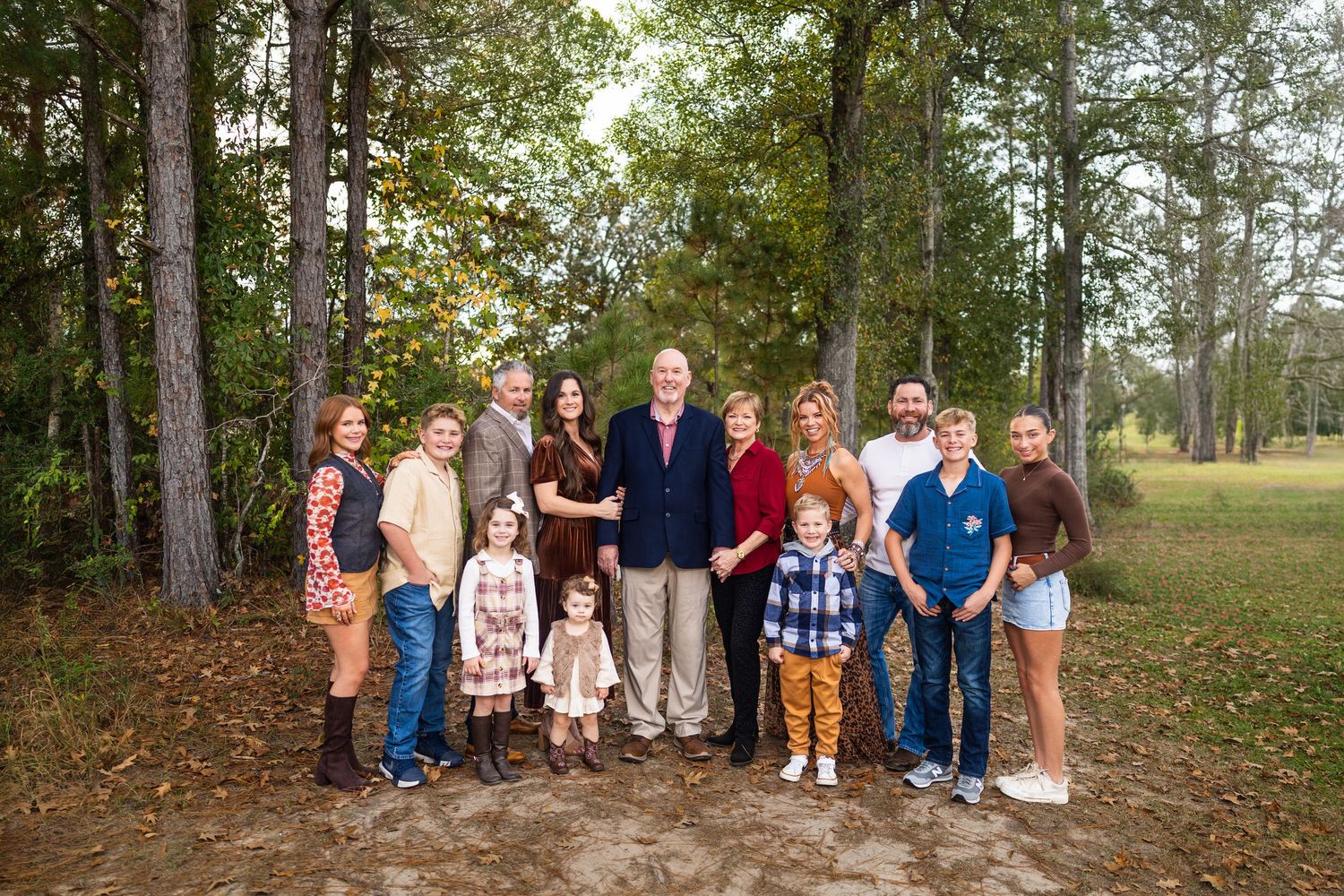 Large family group poses together outdoors in casual clothing.