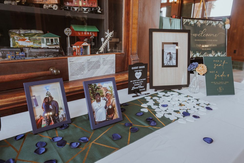 Wedding reception display table with photos and decorative elements.