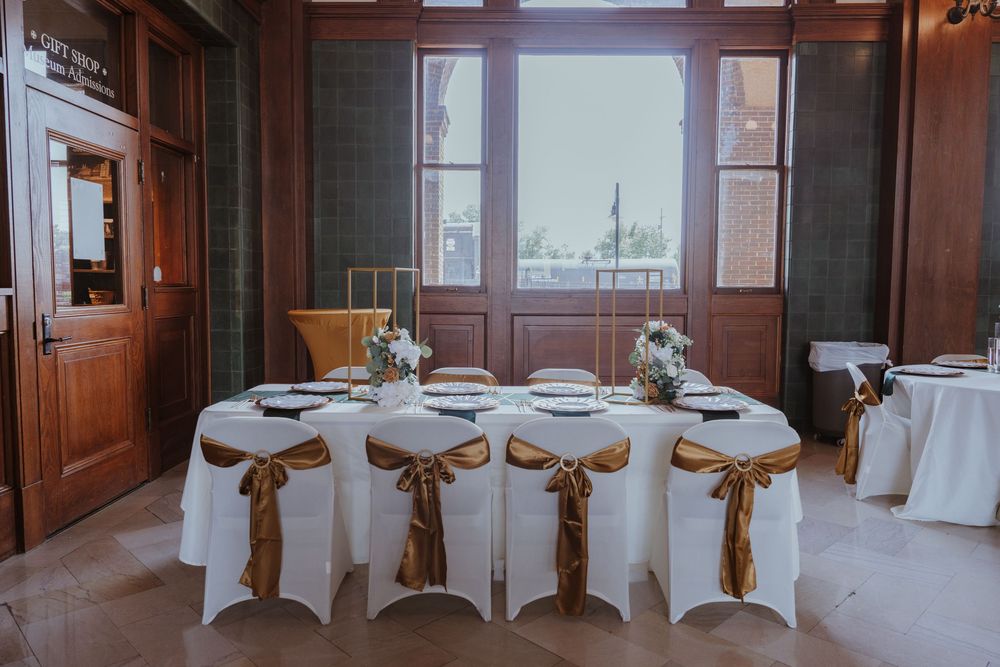 Indoor wedding venue with white-covered chairs and natural lighting.