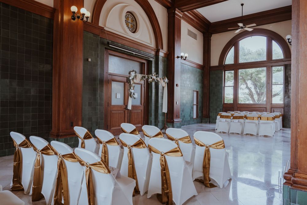 Wedding reception hall with white chair covers and elegant wood paneling.