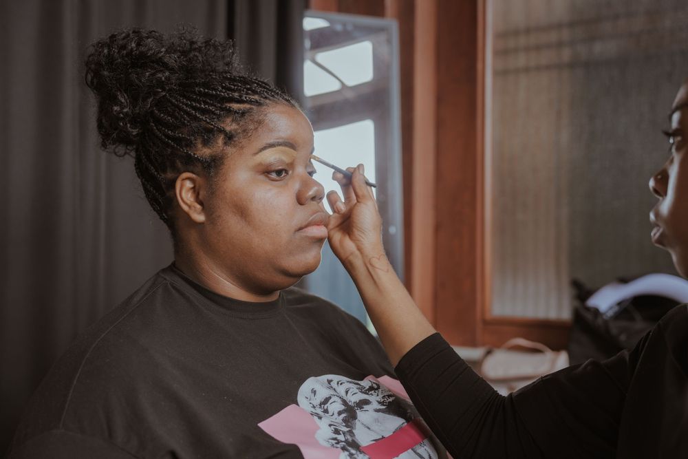 Final touches of wedding makeup being applied in natural window light.