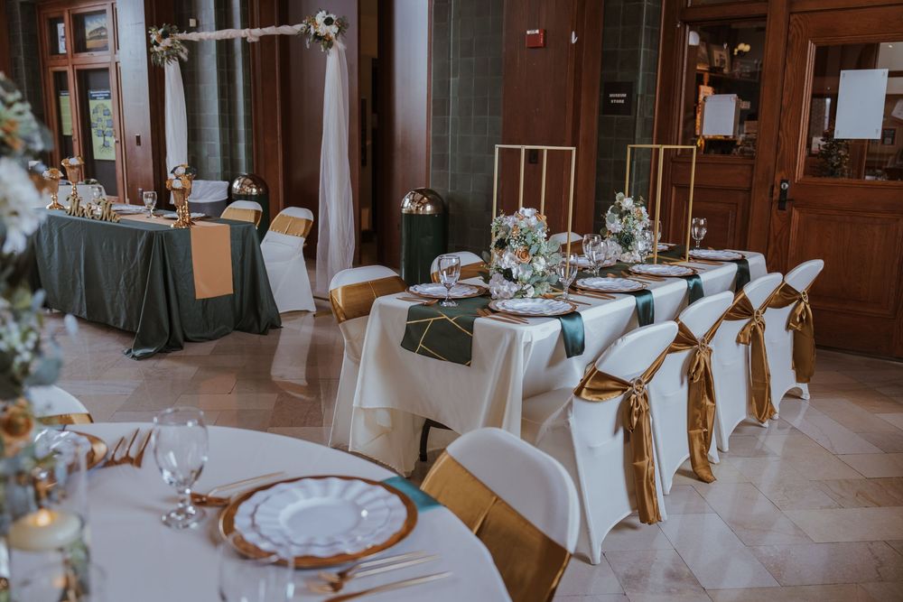 Elegant wedding reception venue with white tablecloths and wooden details in warm lighting.