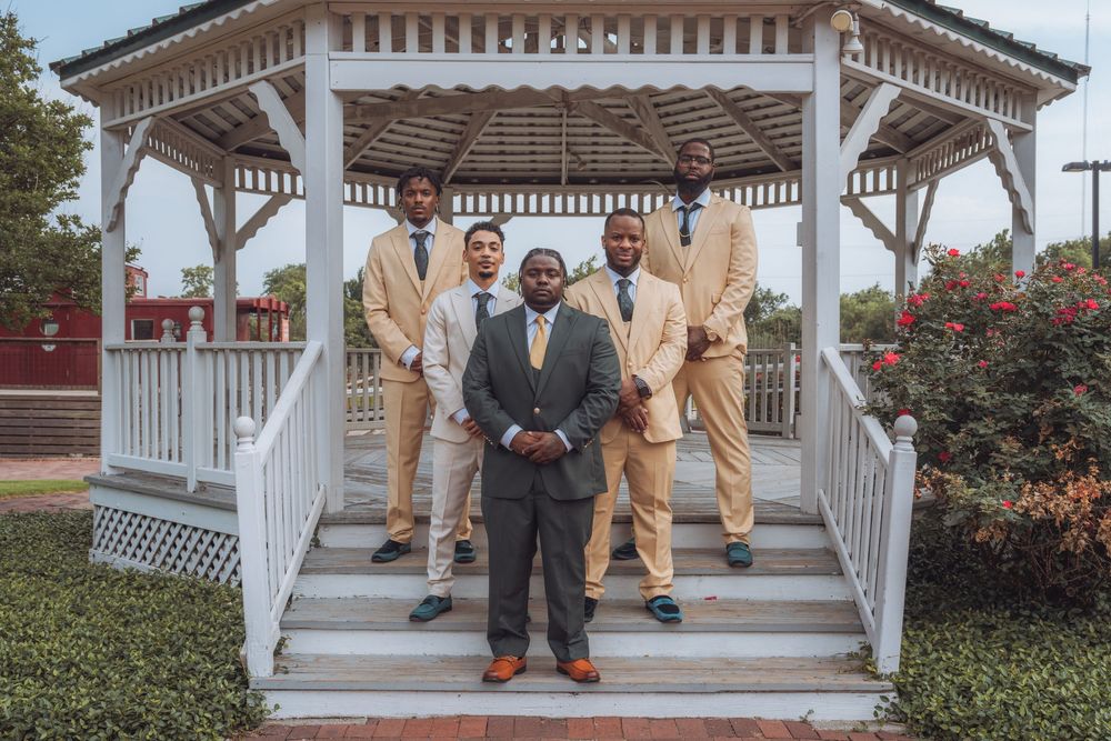 Wedding party posing on white gazebo steps in formal attire.