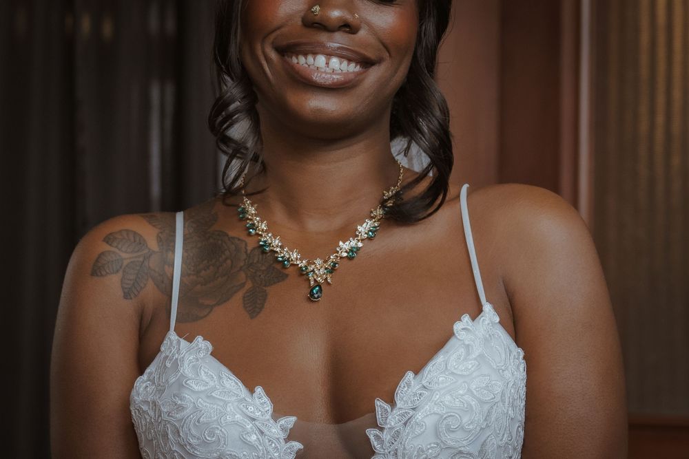 Beautiful bride in white lace dress smiling during wedding preparations.