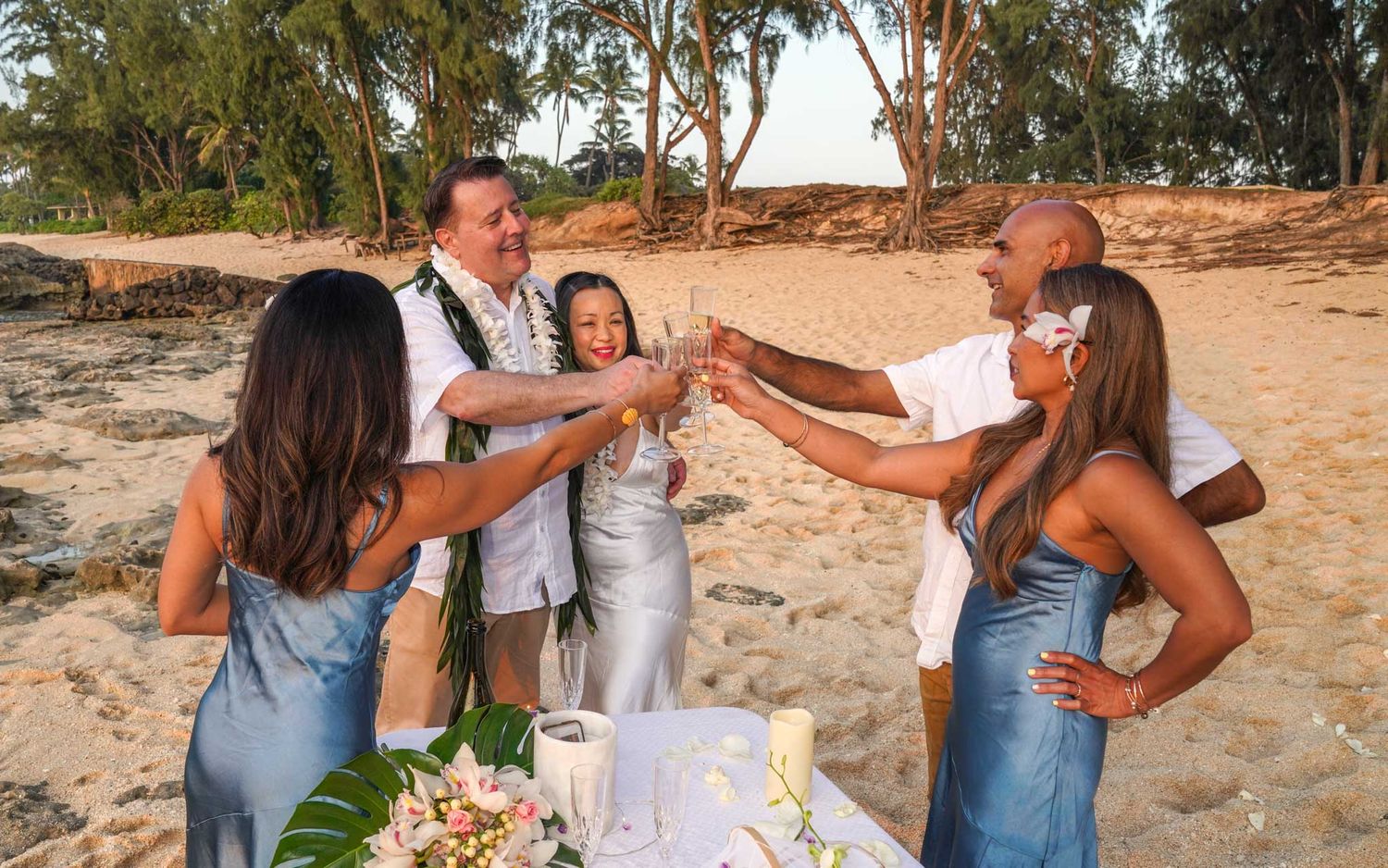 Elopement session taken in Turtle bay, North Shore, Oahu. A wedding group toasts with champagne glasses on a scenic beach during sunset.