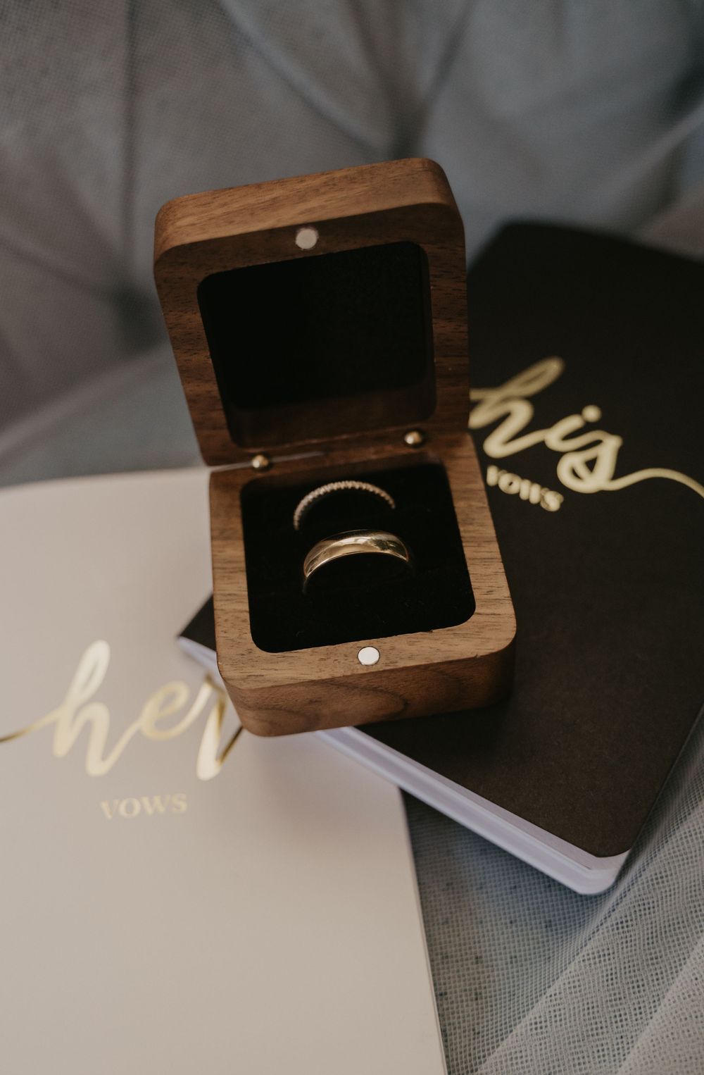 A wooden ring box with a gold wedding band nestled on black velvet is photographed from multiple angles.