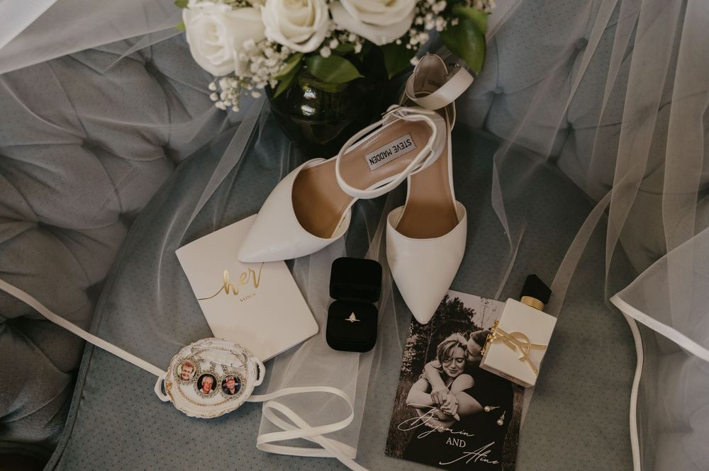 White roses and wedding accessories arranged elegantly on a grey surface.