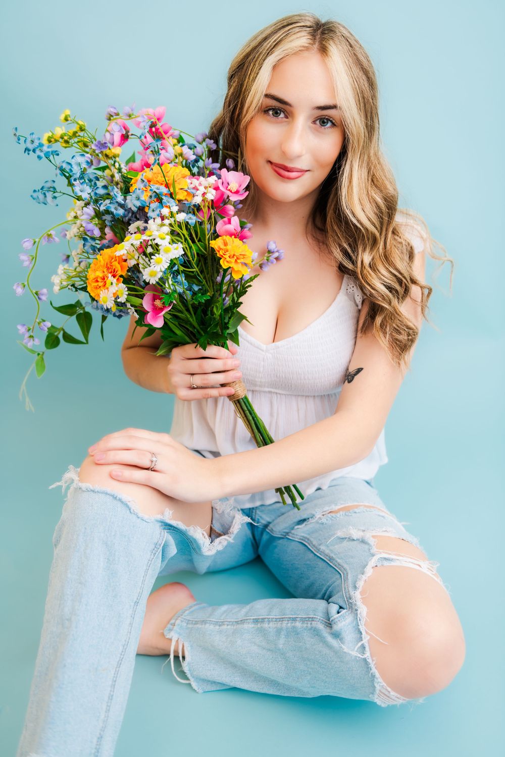 A bright and cheerful wildflower bouquet with pink, yellow and blue blooms against a turquoise background.