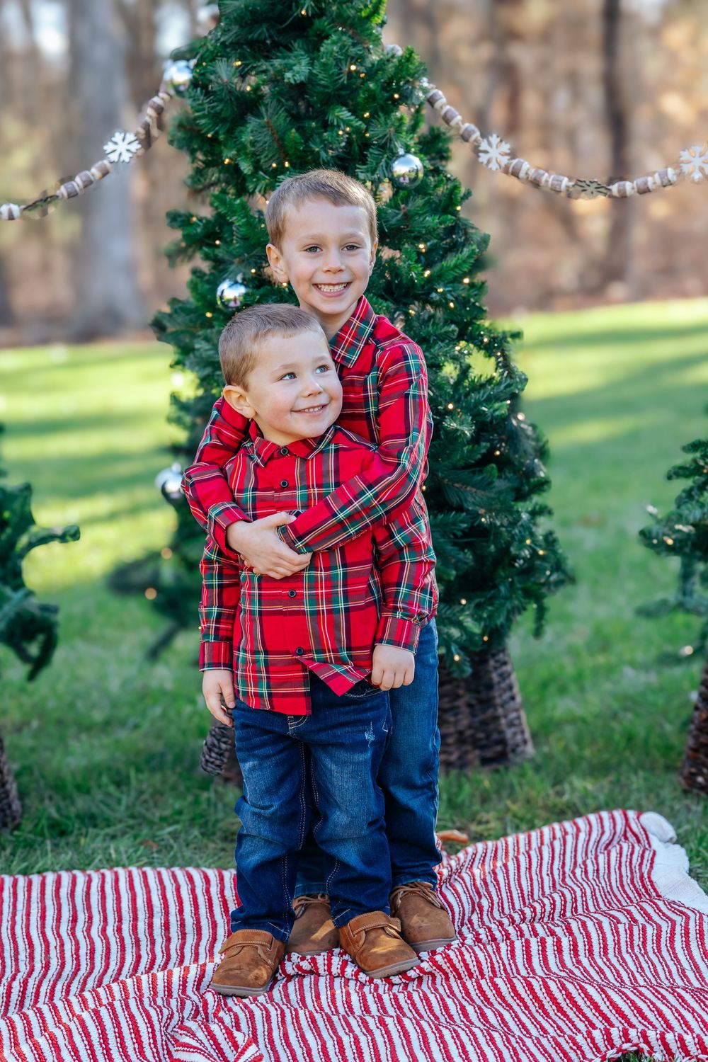 Holiday mini session with child on striped blanket by decorated evergreen tree.