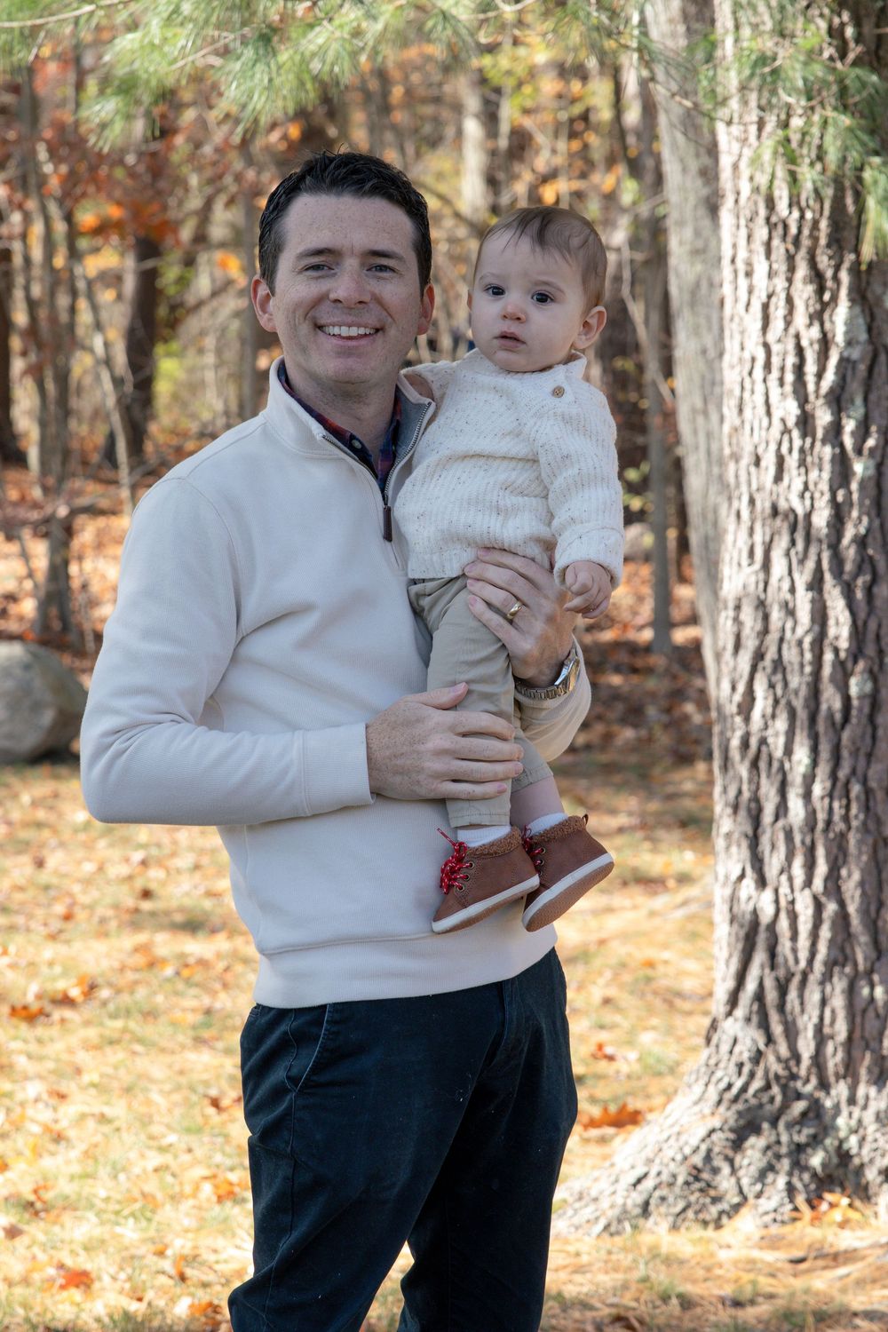 Sweet candid moments captured between parent and child in white sweaters against autumn backdrop.