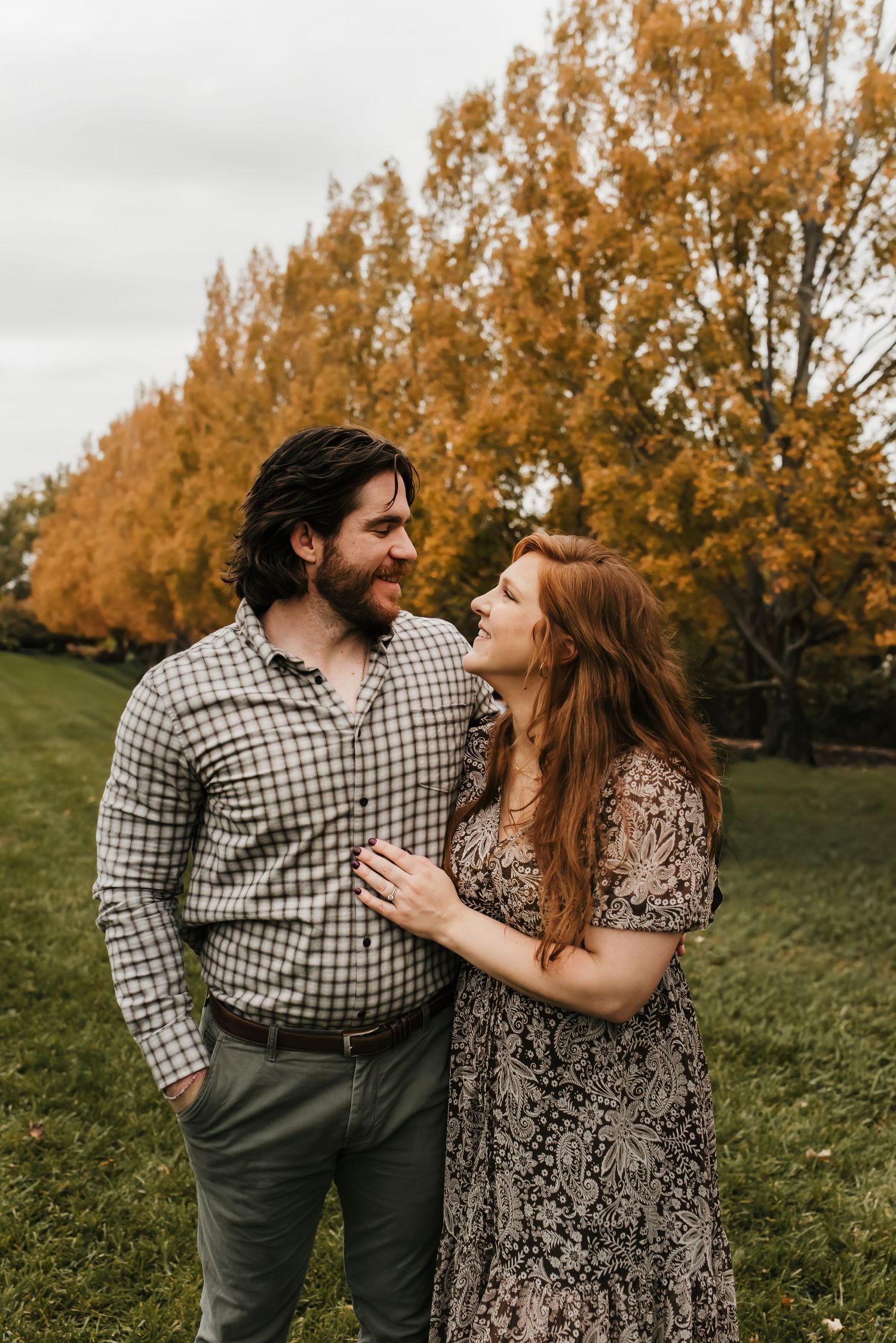 husband and wife look adoringly at one another during their adult park family photo session