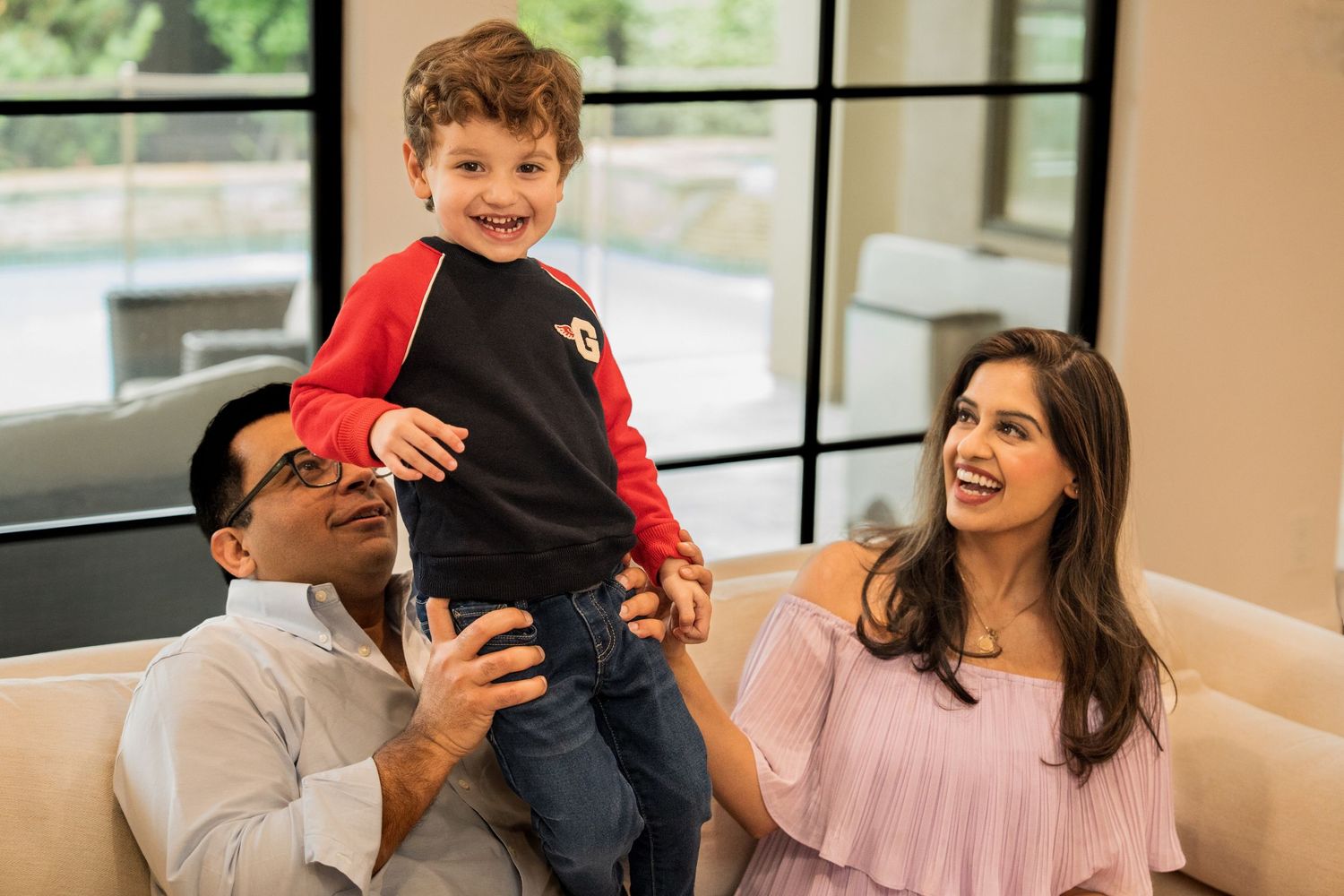 Family shares joyful moments together while relaxing on a comfortable beige couch in a bright living room.