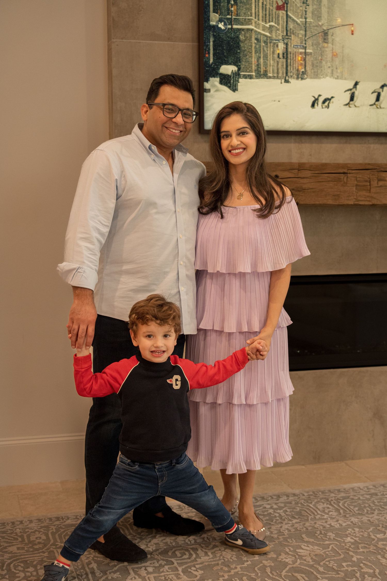 A family poses together on a stone floor with a young child wearing a Mickey Mouse shirt.