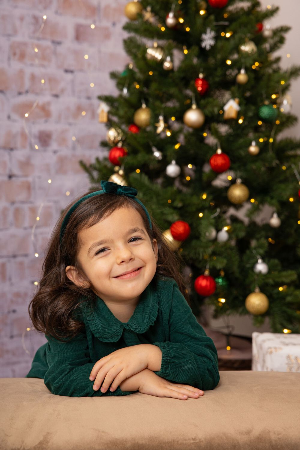A festive holiday portrait against a decorated Christmas tree with twinkling lights.