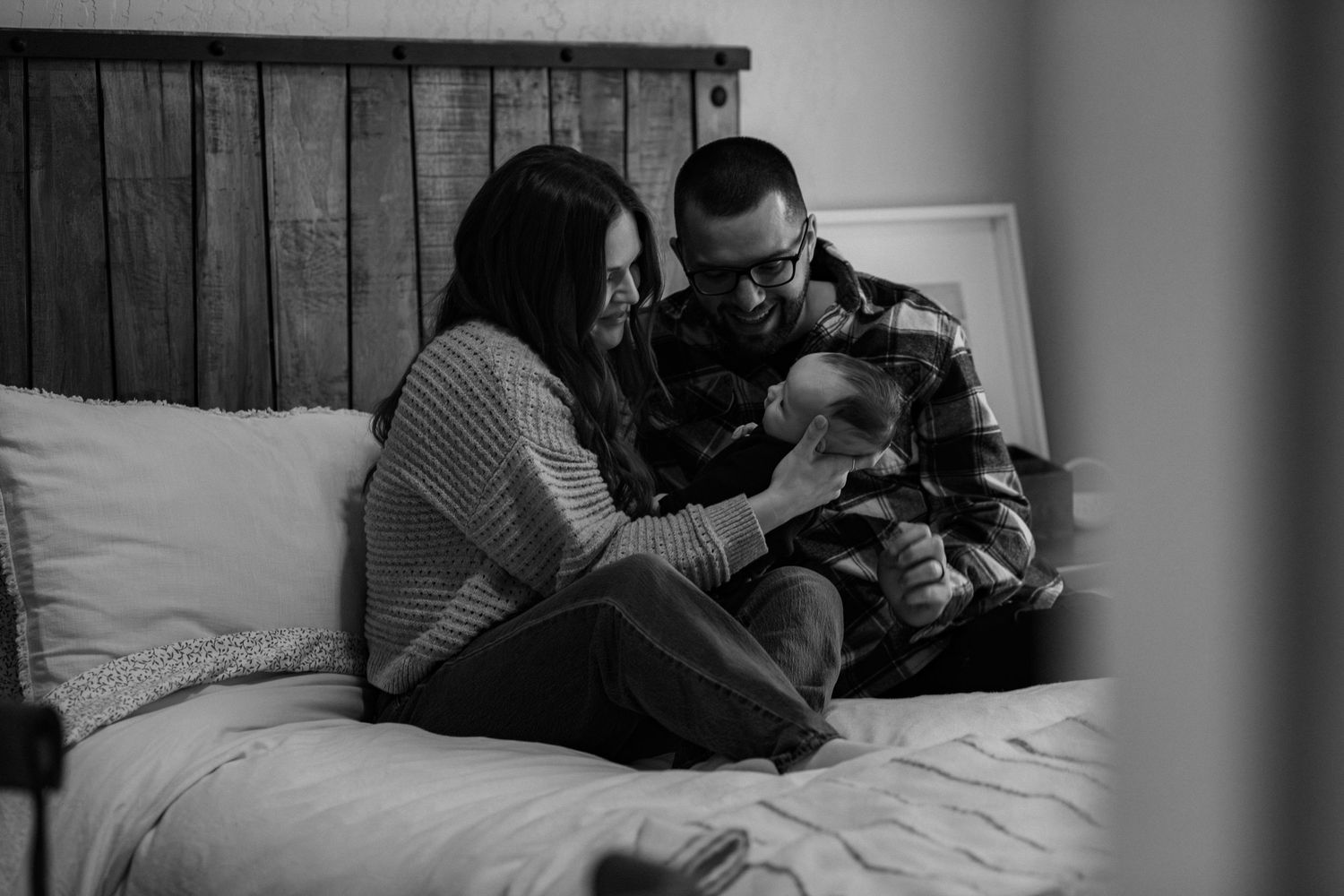 A couple shares an intimate moment together while lying on a white bed.