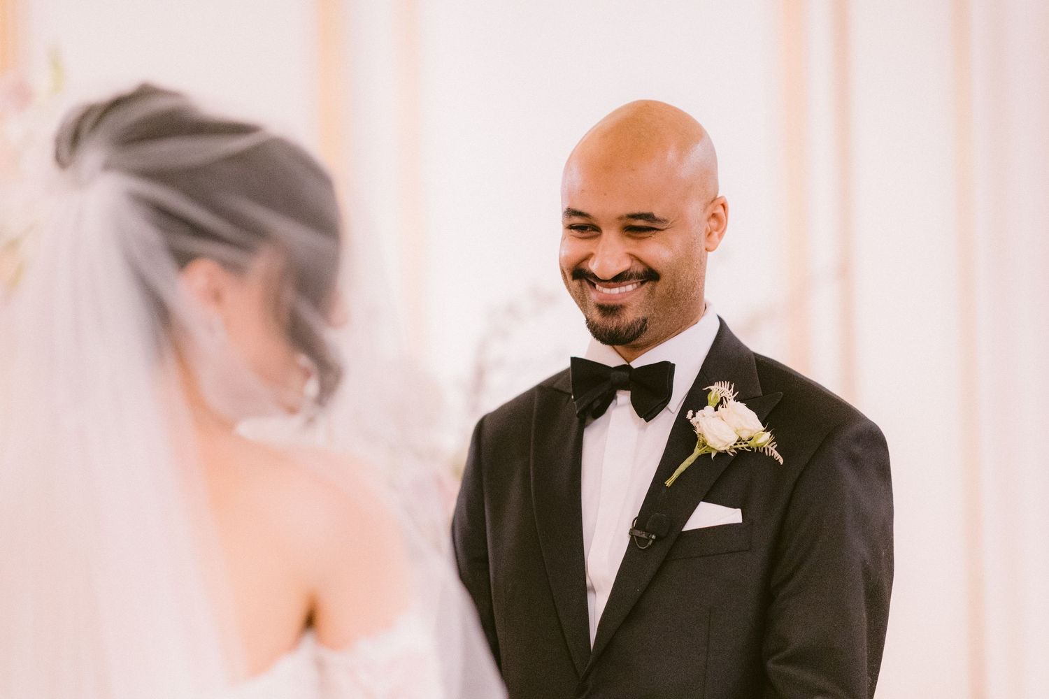 A joyful moment captured during a wedding ceremony with the groom in a classic black tuxedo and bowtie.