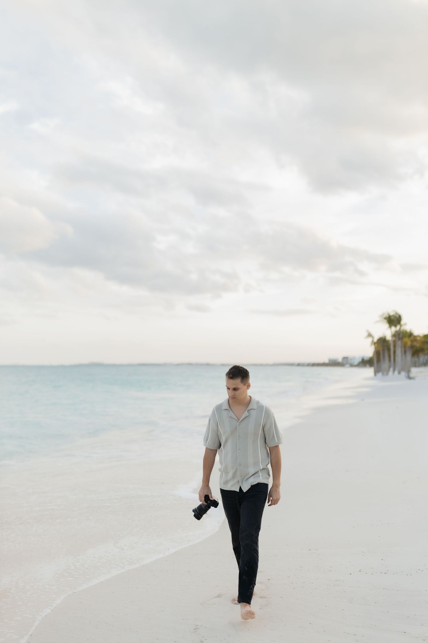 Wedding photographer Marco walking along the beach in Mexico while documenting a destination wedding.