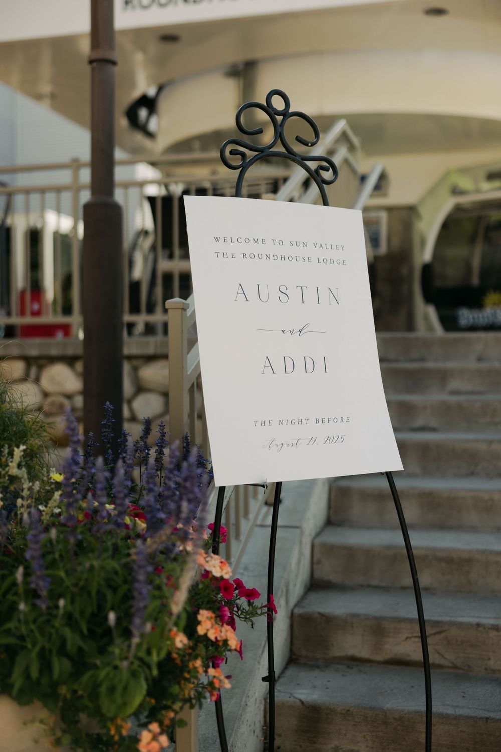 Wedding signage displays on black stands with colorful flowers decorating the steps.