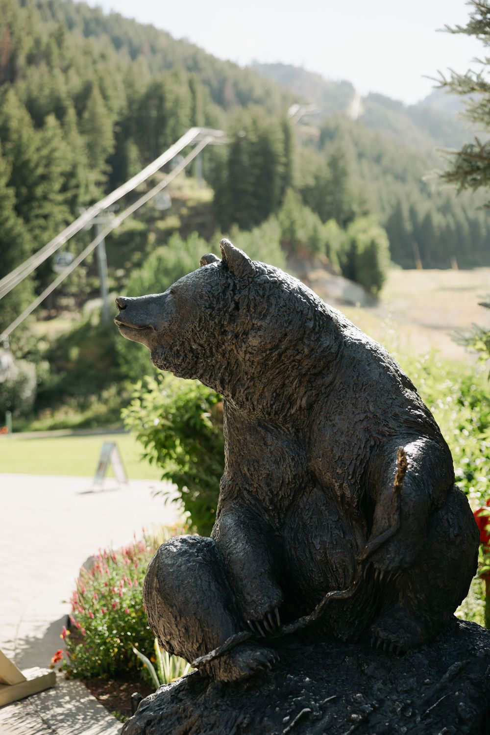 A large black bear sculpture sits in a scenic mountain landscape.