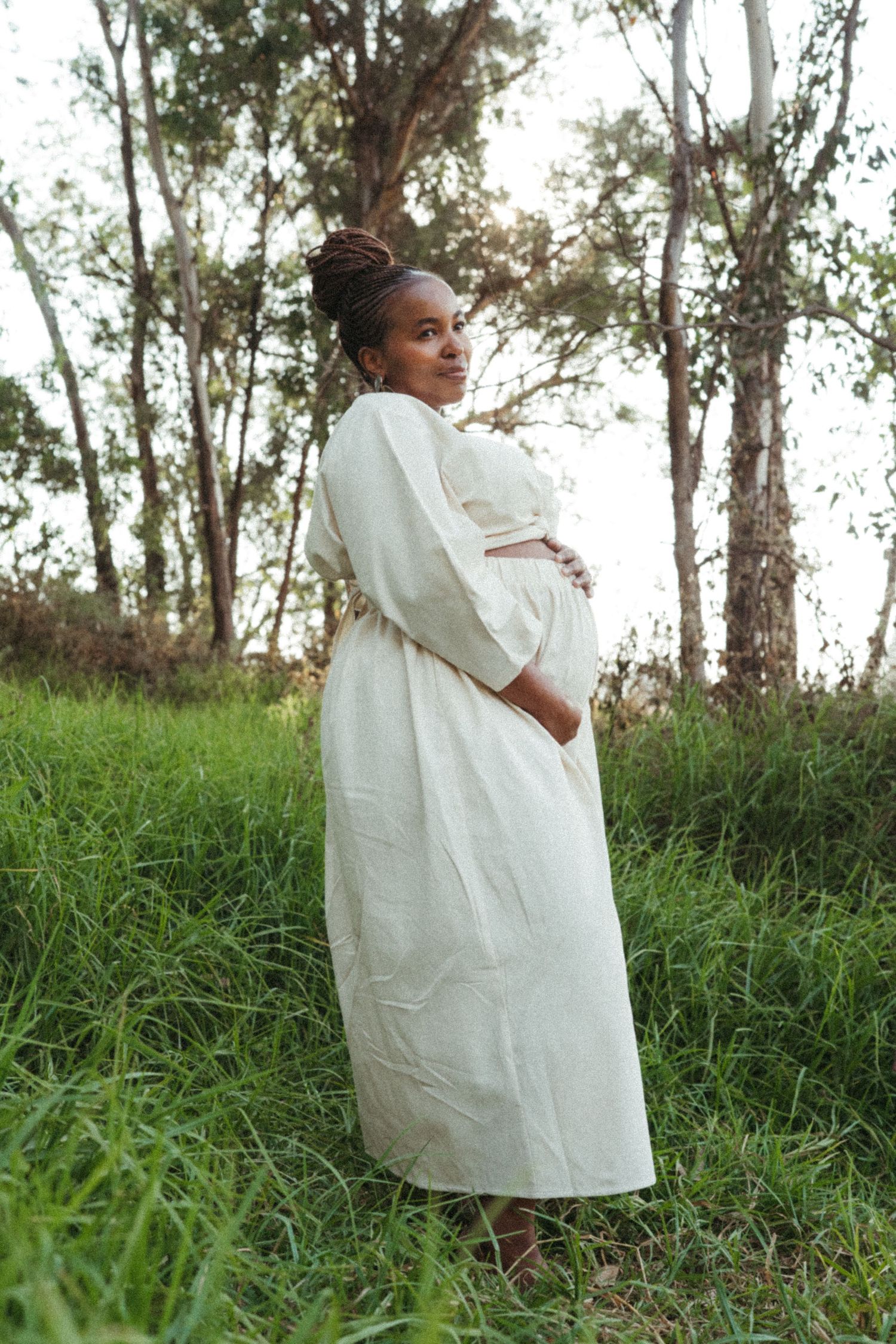 Artistic outdoor photography showing someone in white clothing surrounded by lush greenery.