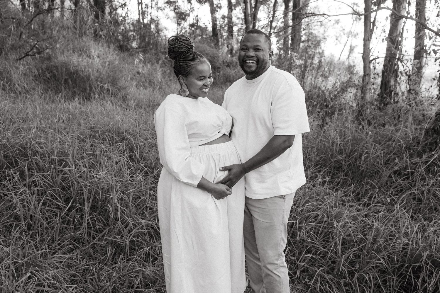 Romantic black and white photo of a couple in white clothing sharing a tender moment.