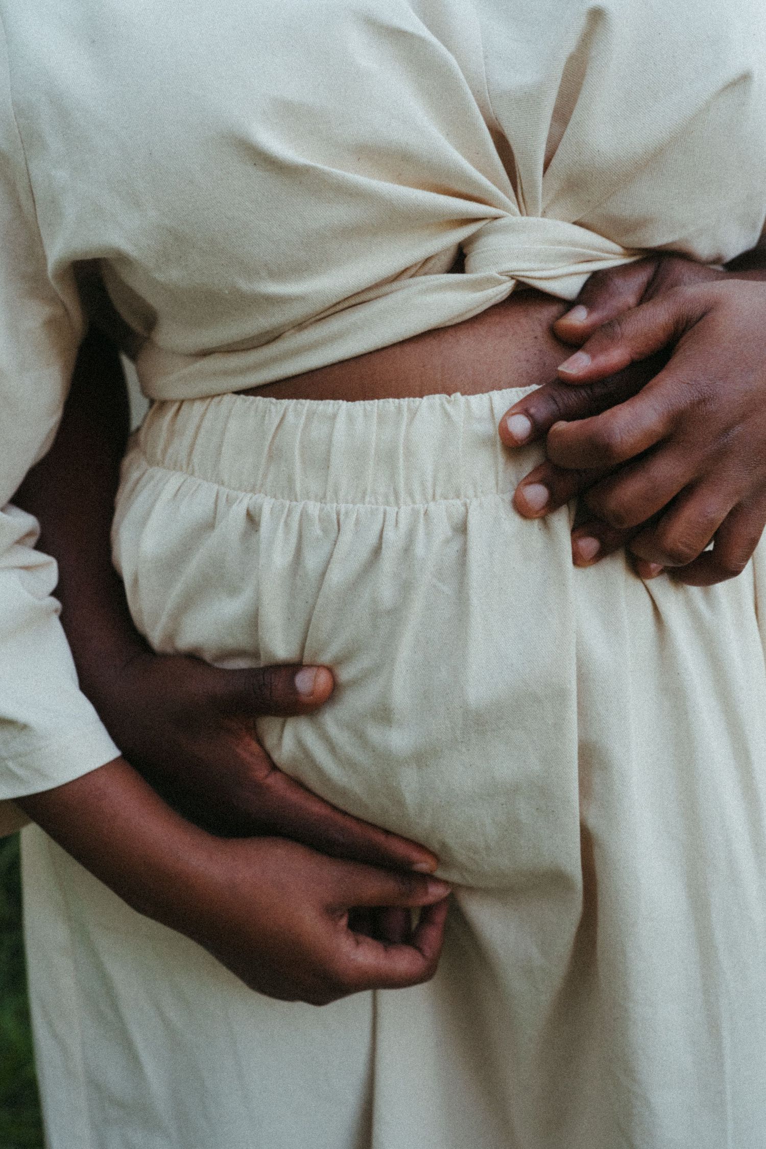 Detail shot of hands tenderly holding a white fabric-covered waist.