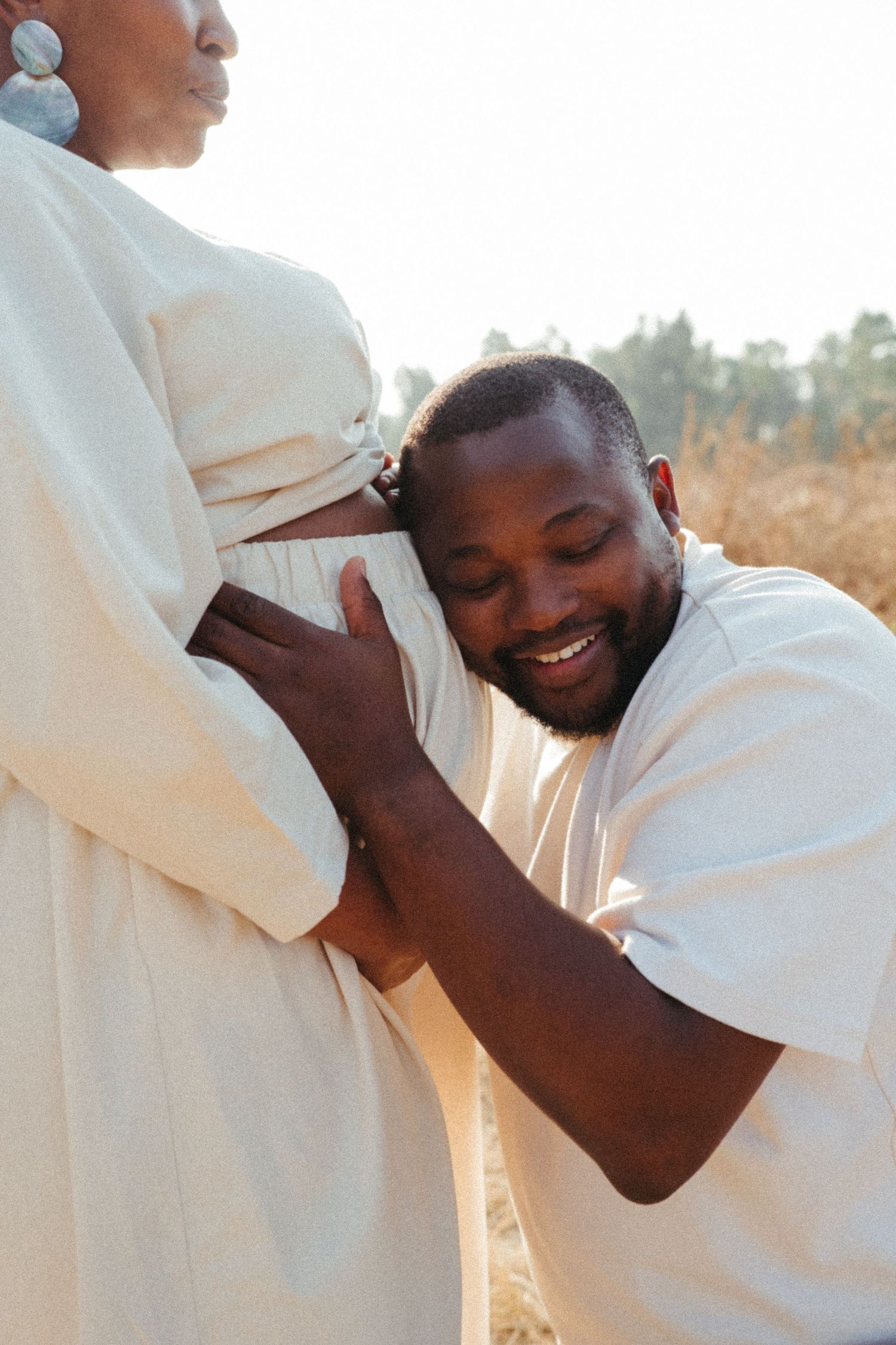Tender moment between couple as they embrace during outdoor maternity photoshoot.