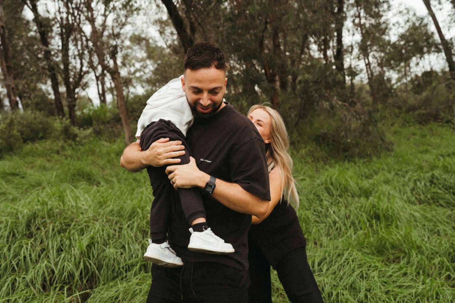 A candid moment captured between two people hugging and smiling in a grassy field.