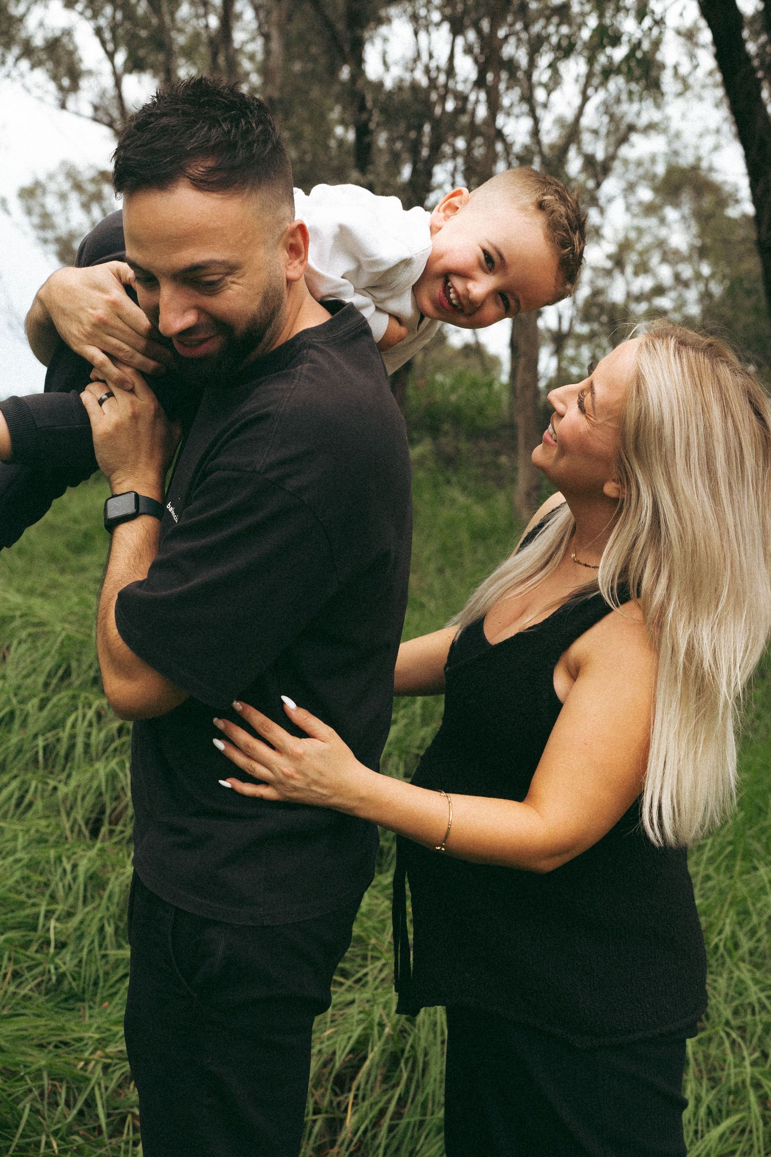 A couple shares playful candid moments together in a grassy outdoor setting.