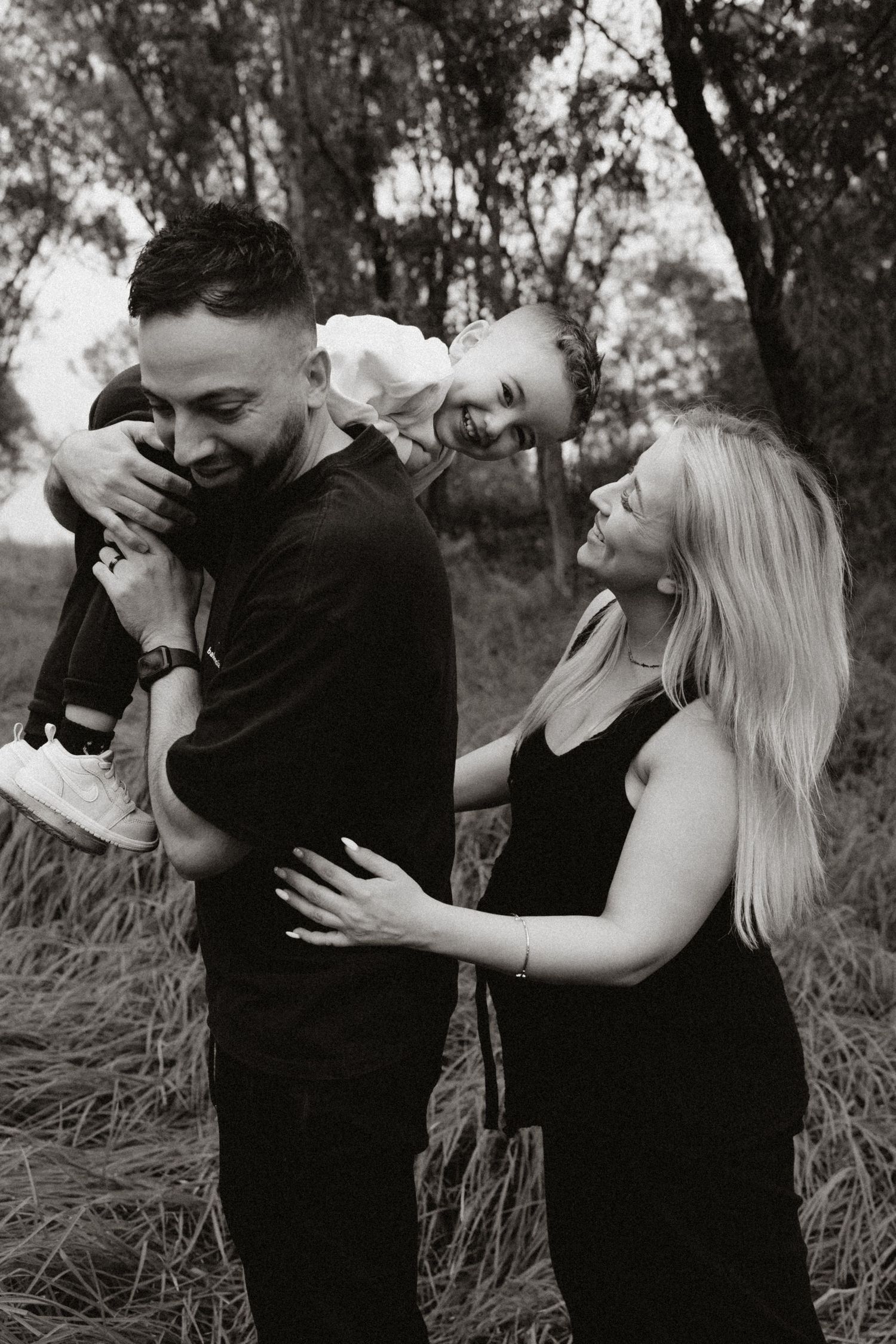 Black and white photo of a couple laughing and embracing in a natural setting.