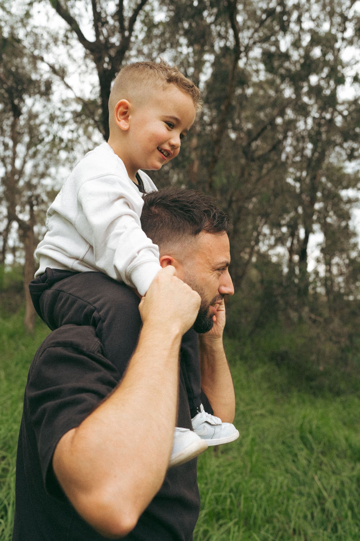 Parent and child sharing playful piggyback ride in grassy outdoor setting.
