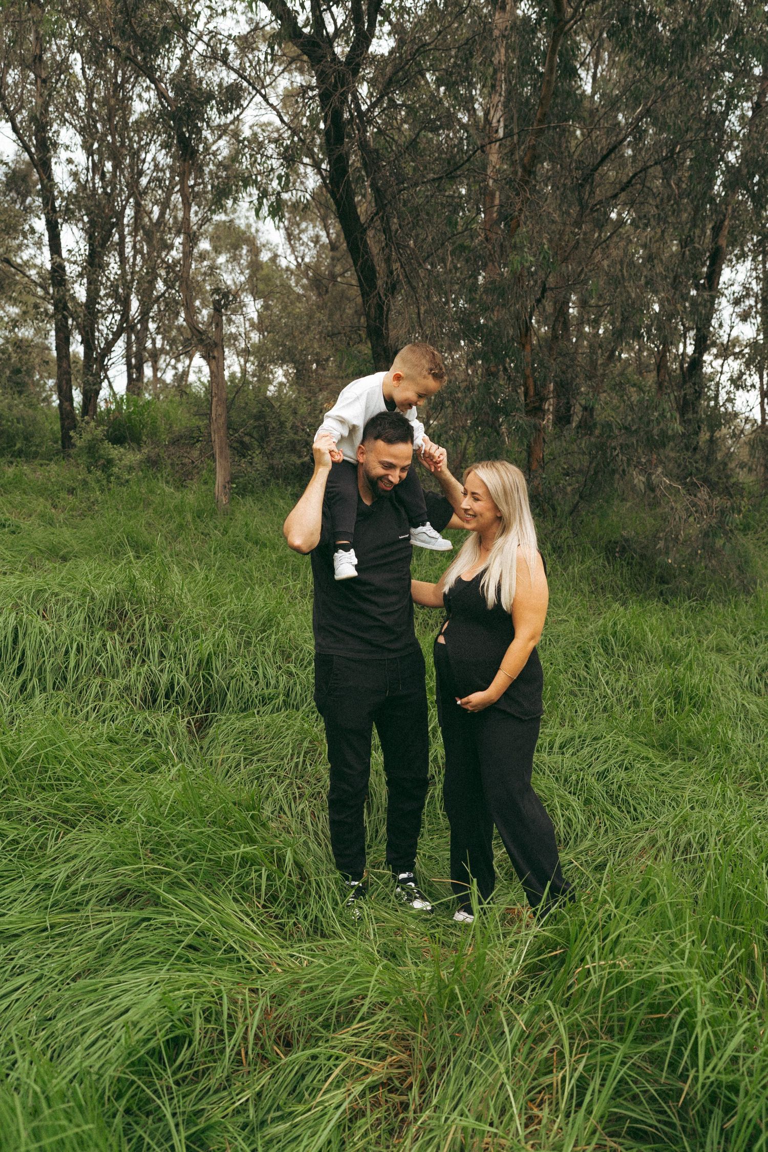A couple sharing intimate moments while standing in long grass on a sunny day.