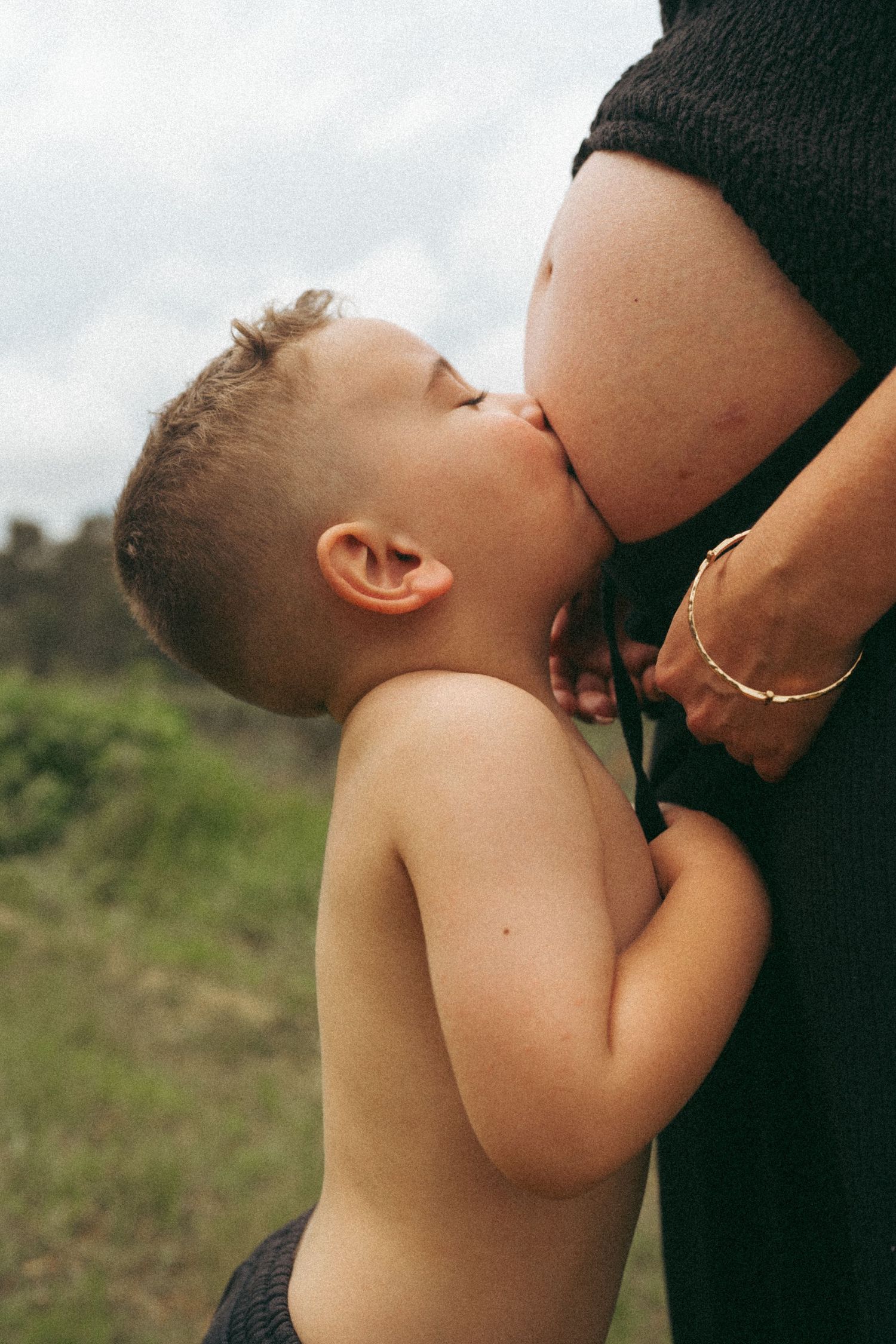 A sweet capture of a child giving a gentle kiss to an expectant mother's belly.