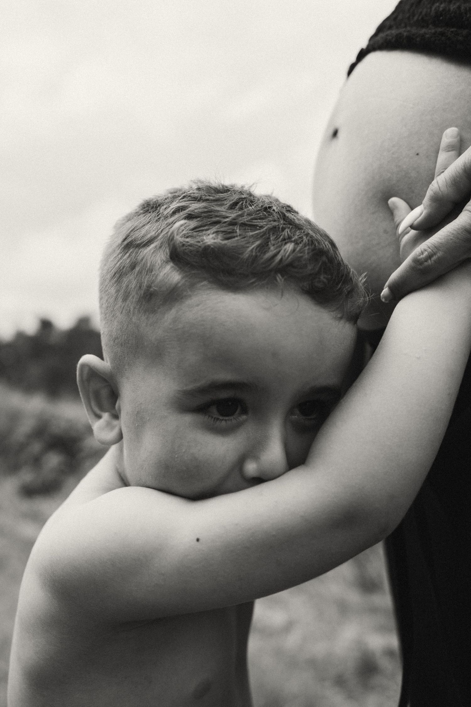 A black and white image showing a child embracing a pregnant belly with emotion.