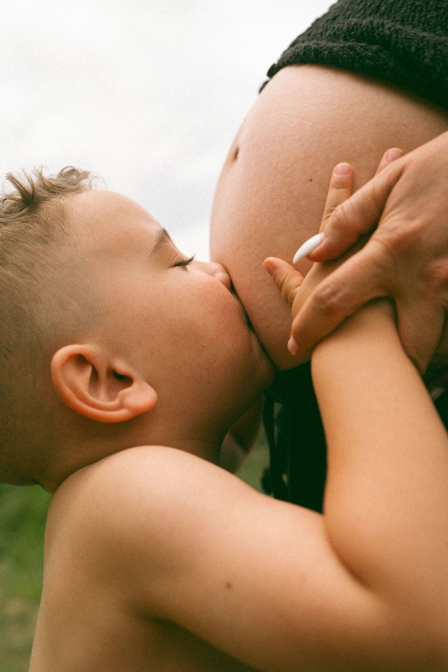 A tender photograph showing a child's gentle interaction with an expectant mother's belly.