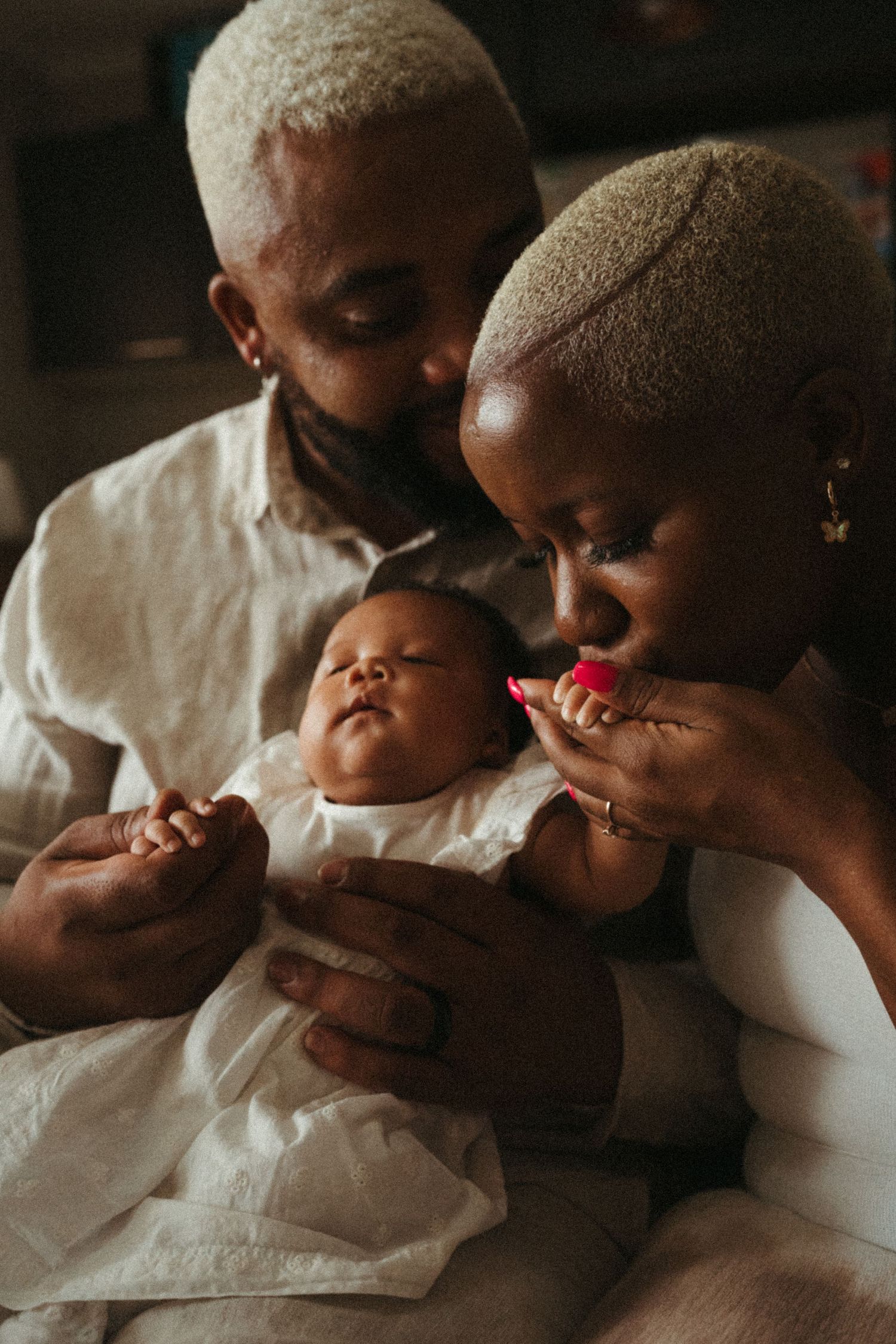 A warm family moment captured as parents admire their infant in white clothing.