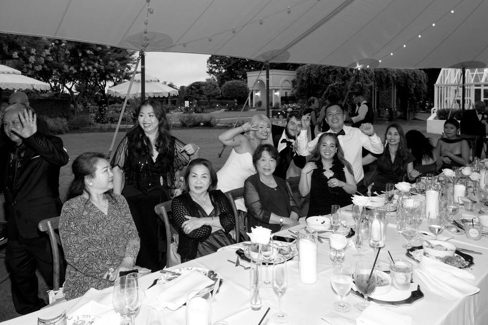 A panoramic view of people seated at a long dining table during a social gathering or event.